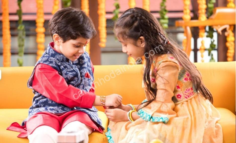 irma-amarrando-rakhi-no-irmao-pequeno Irmão mais novo olhando atentamente enquanto a irmã amarra o rakhi em sua mão durante o Raksha Bandhan