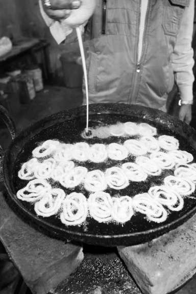 pessoa-preparando-jalebi Pessoa preparando jalebi indiano em óleo quente