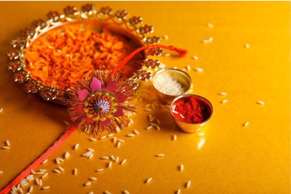 rakhi-itens-celebracao-raksha-bandhan Rakhi disposto em uma bandeja com flores, doces e outros artigos usados no festival de Raksha Bandhan