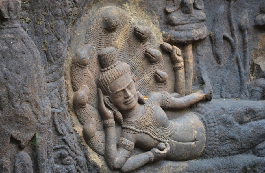 vishnu-deitado-shesh-naag-templo Detalhe de uma escultura antiga mostrando Vishnu repousando sob o capuz da serpente Shesh Naag, localizada em um templo histórico da Índia