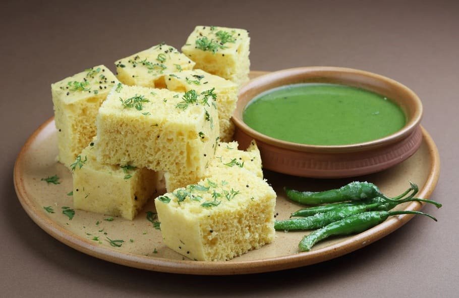 dhokla-cremoso-com-chutney-verde Dhokla cremoso acompanhado de chutney verde, uma combinação deliciosa de sabores suaves e picantes da culinária indiana