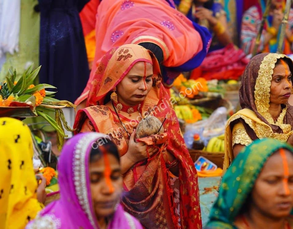 Mulheres em oração nas margens do rio, expressando devoção e fé durante o ritual sagrado