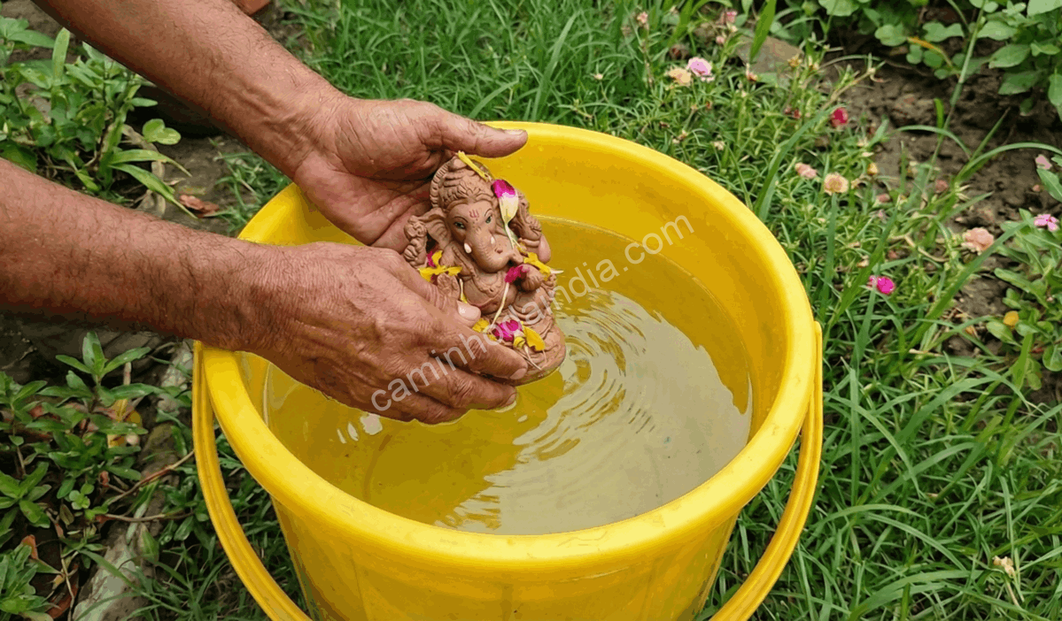 Pessoa realizando o visarjan de um ídolo em um balde no jardim de sua casa